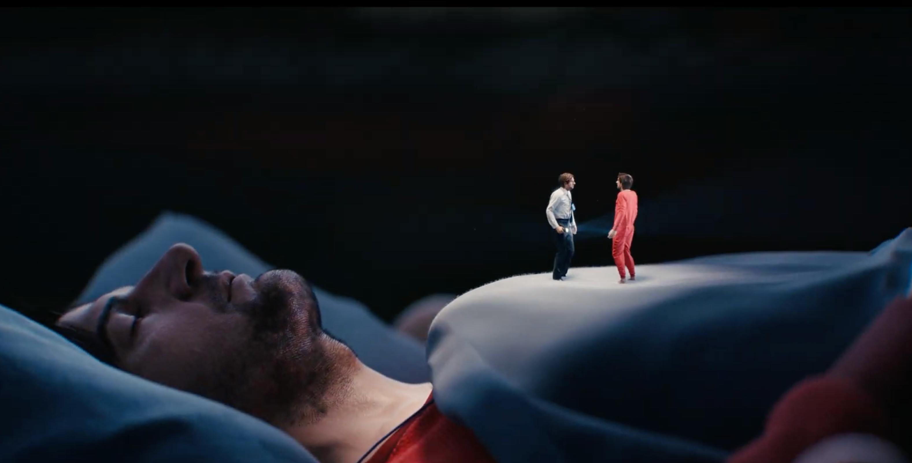 A cinematic, low-angle shot of a person lying down, with vibrant red and blue lighting creating a moody, dramatic atmosphere.
