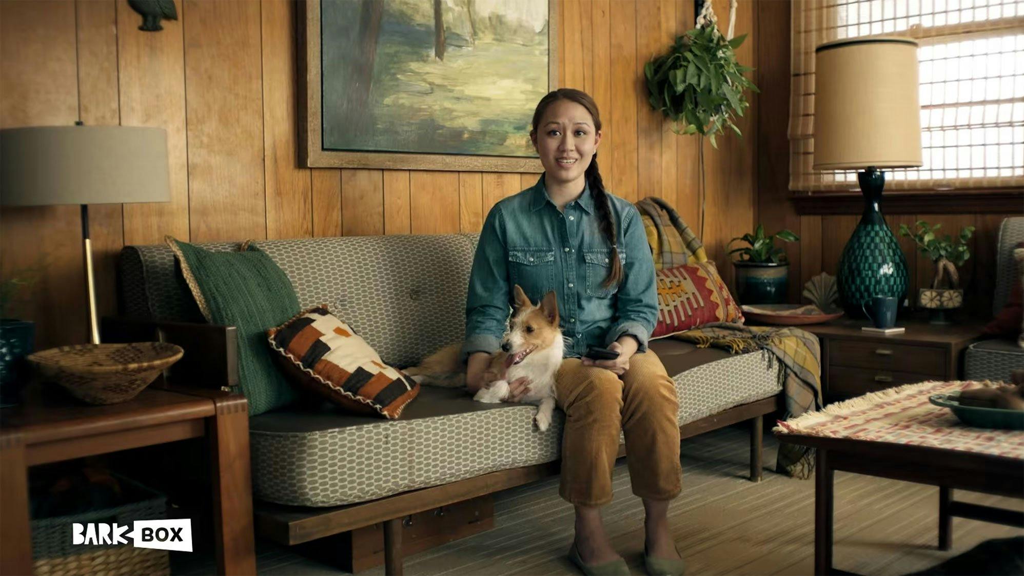 Woman sitting on a couch with her dog in a cozy home setting, showcasing comfort, companionship, and lifestyle branding.