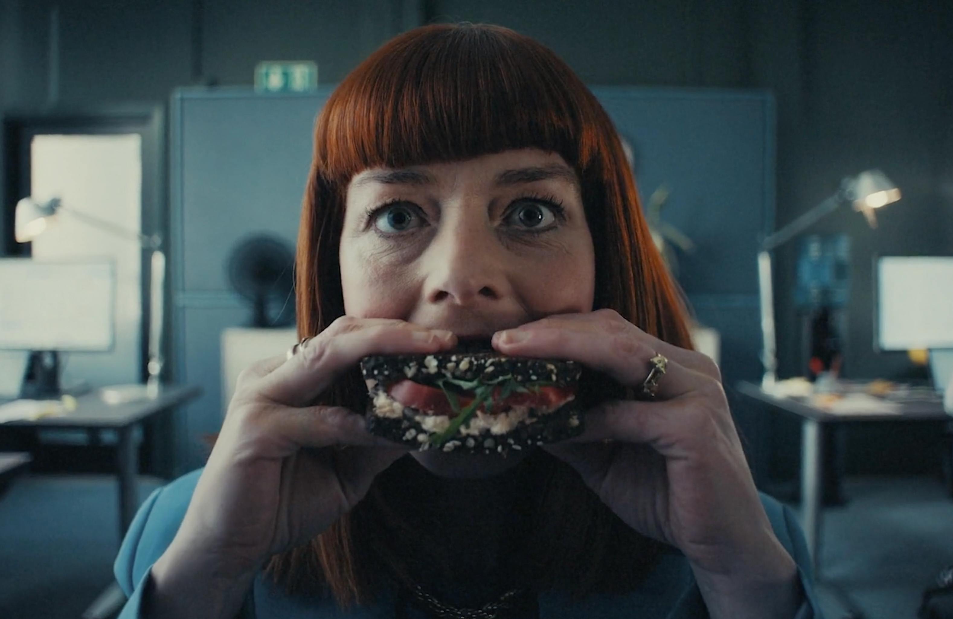 A woman biting into a burger or sandwich.