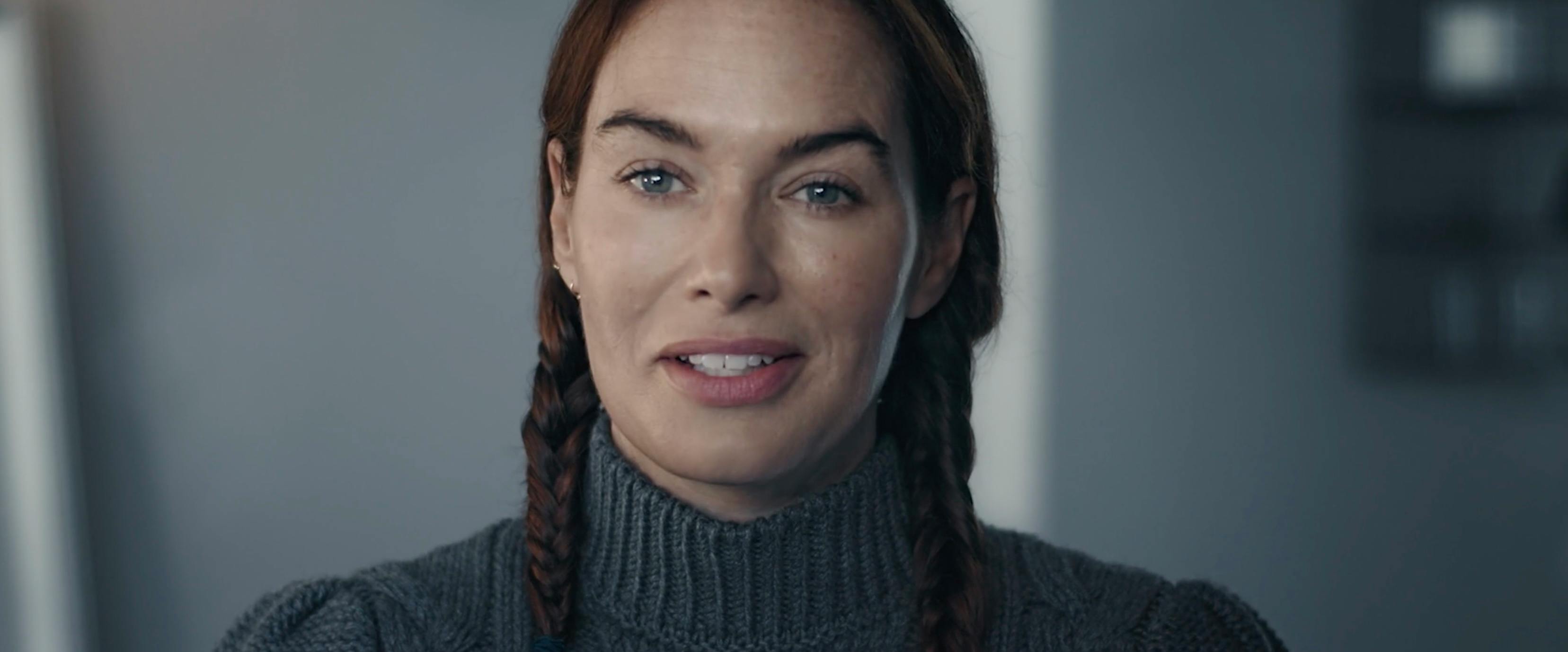 A tight close-up portrait of a megan fox with braided hair wearing a grey turtleneck. The lighting is soft and neutral, focusing on her natural expression and clear skin for a character-driven dramatic shot.