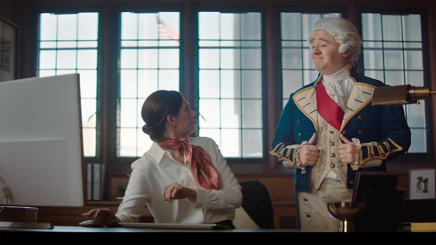 Man in historical costume with woman in office setting, representing creative storytelling and cinematic production in professional video content