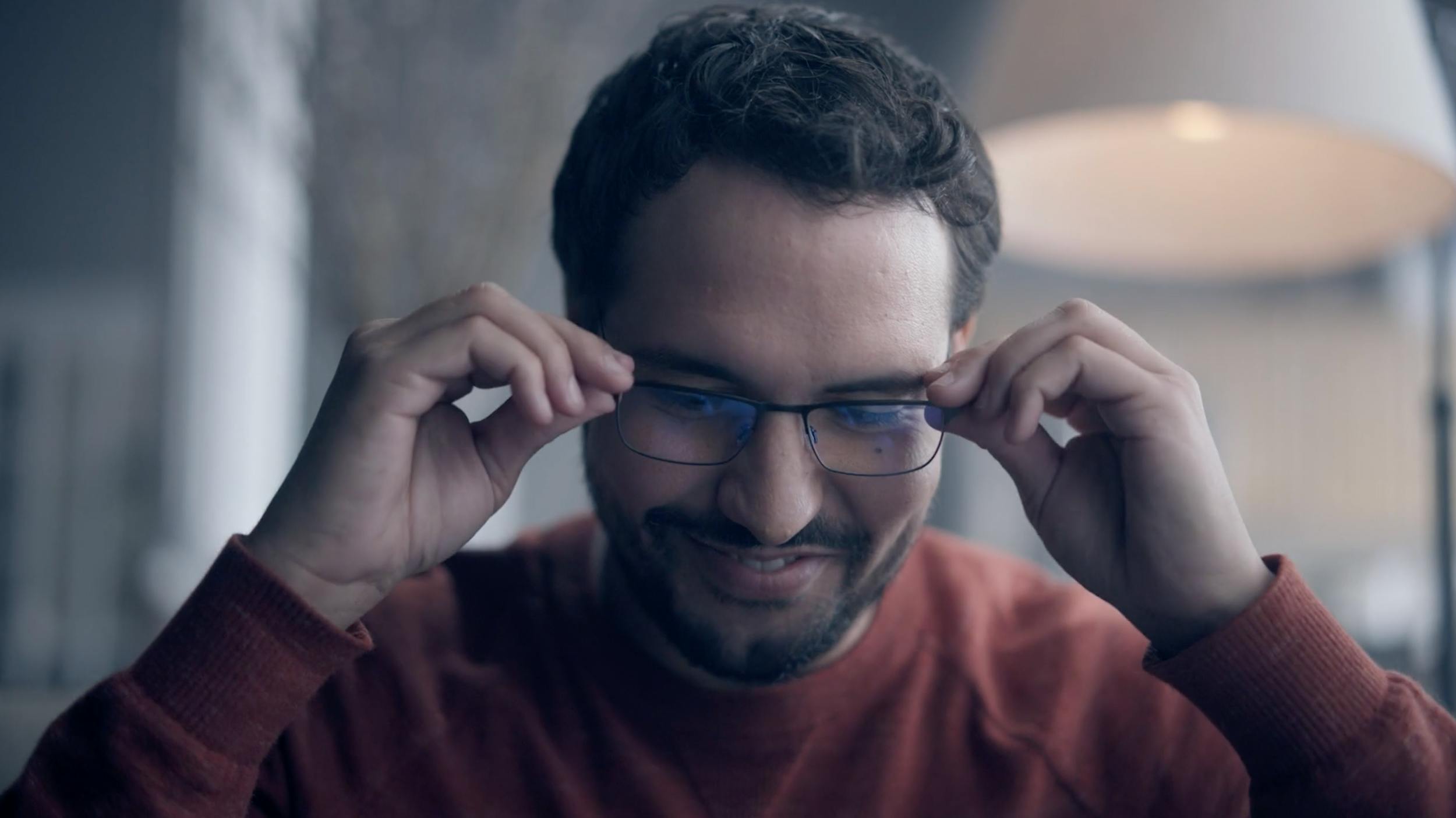 Man adjusting his glasses with a smile, capturing confidence, personality, and relatable everyday moments.