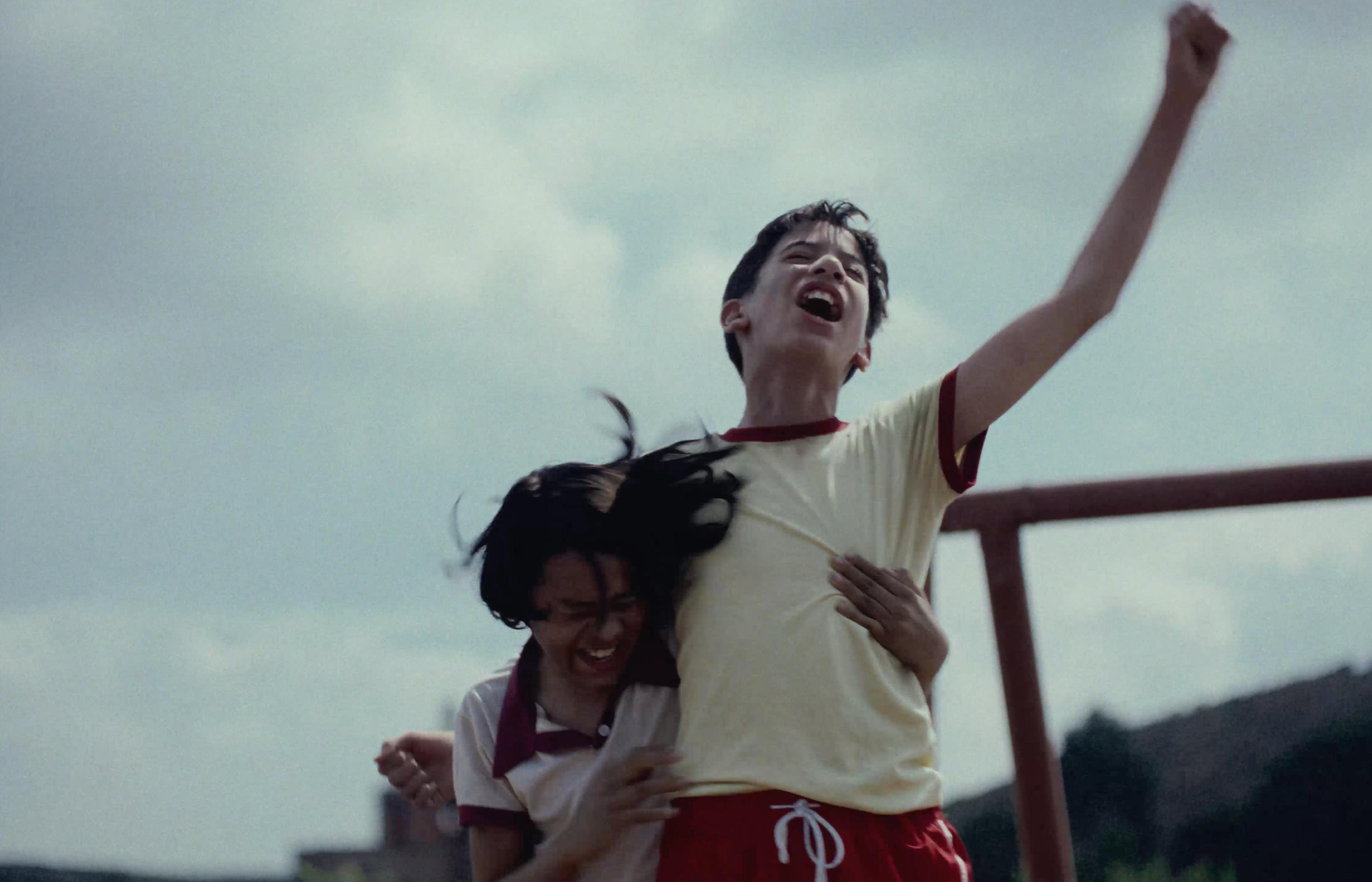 A person with arms raised in a joyful pose outdoors.