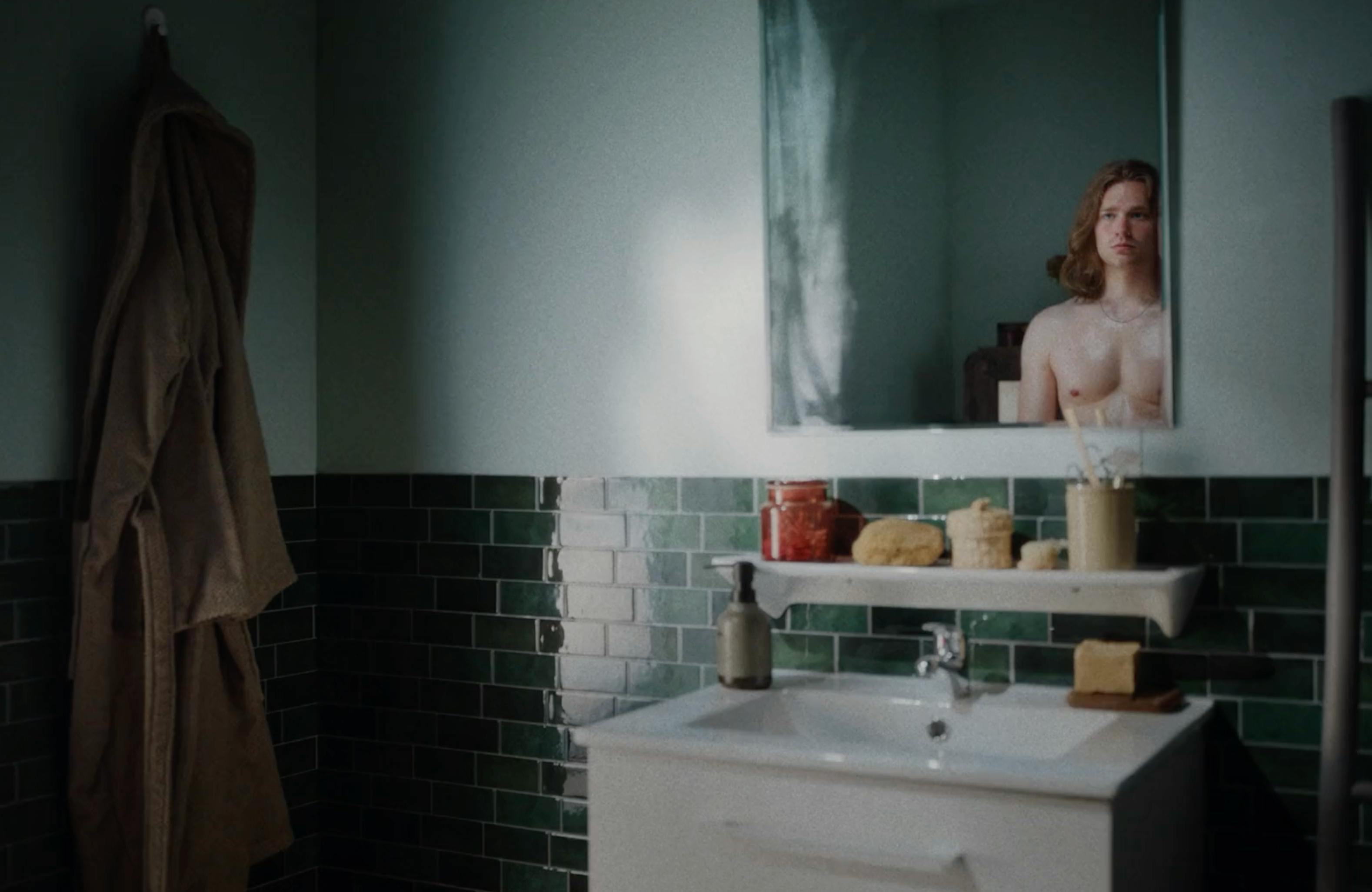 A close-up of a person’s arm and torso in a domestic setting, possibly a kitchen, with soft natural lighting.