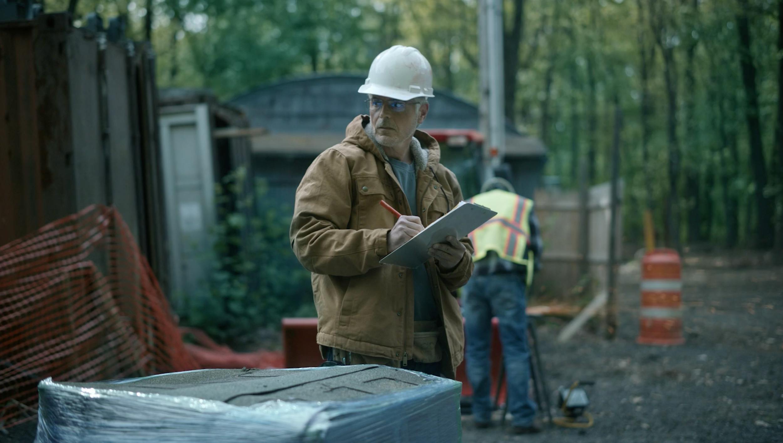 Location scout in a hard hat recording notes for a production shoot.