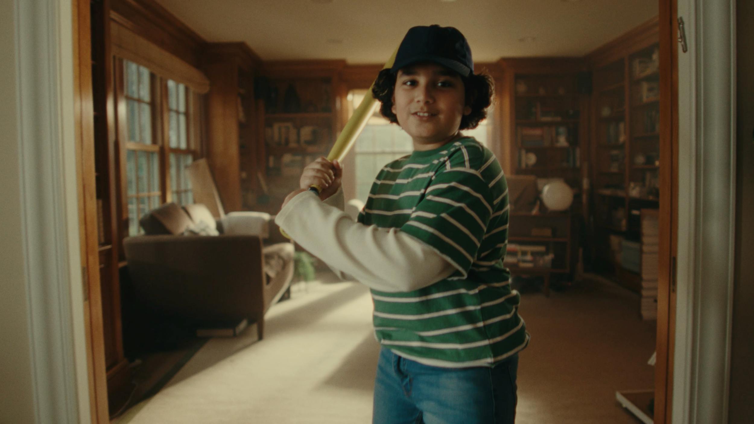 Young boy holding a baseball bat indoors, capturing playful imagination and childhood storytelling.