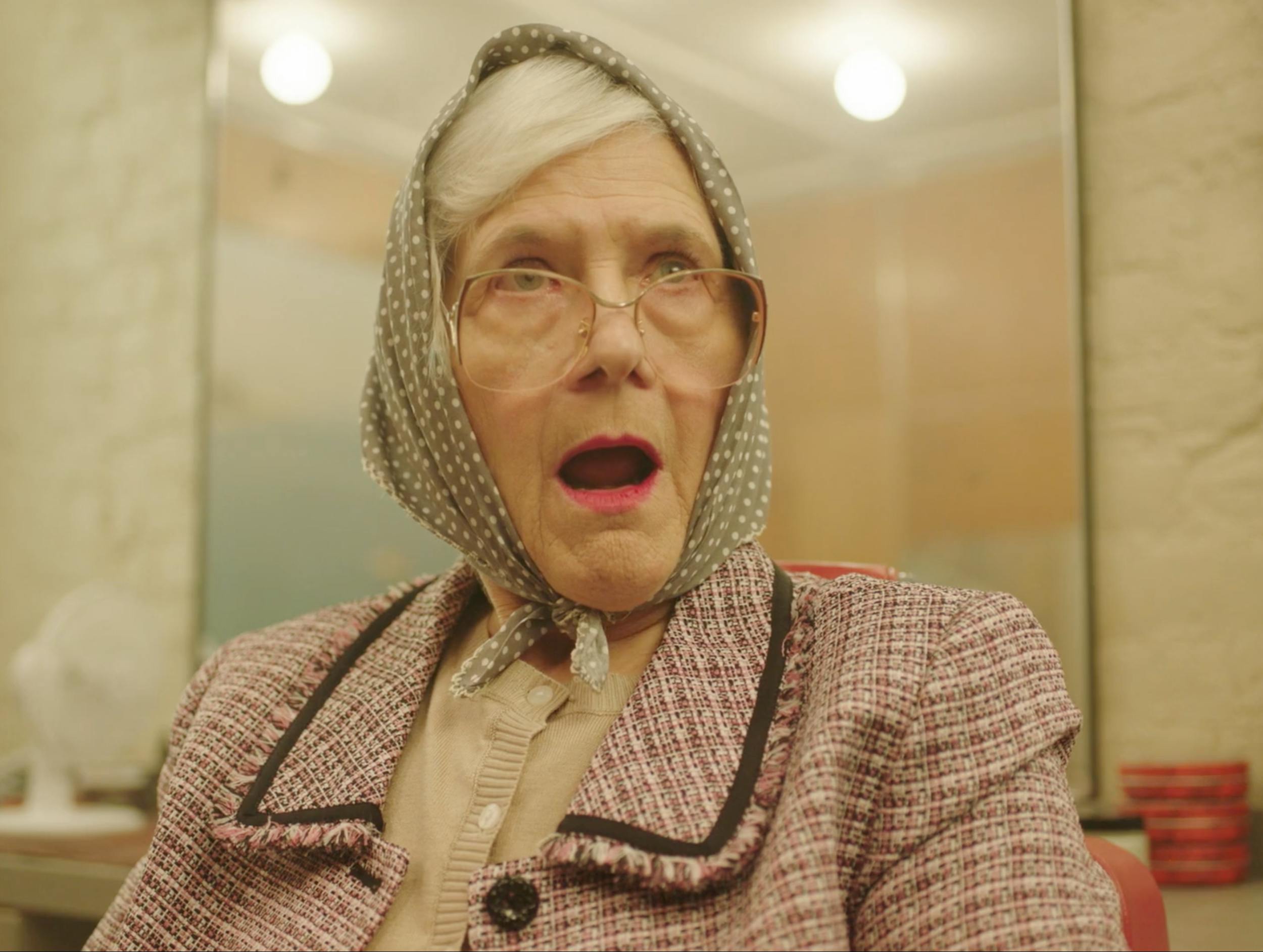 Elderly woman with surprised expression indoors, representing character-driven storytelling and cinematic scenes in professional video production