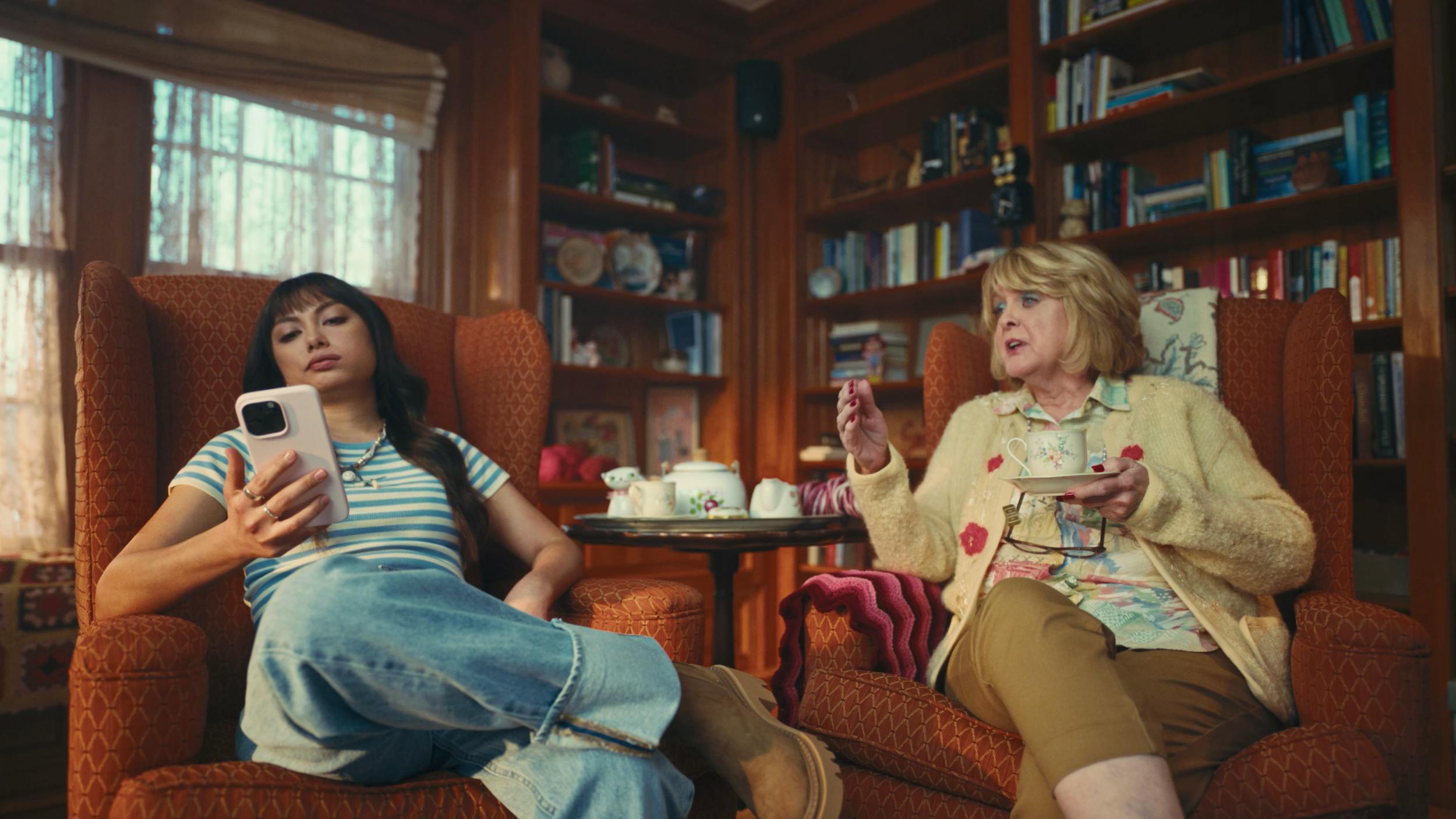 Two women relaxing in a cozy living room, one using a smartphone, representing lifestyle storytelling and everyday scenes in professional video production