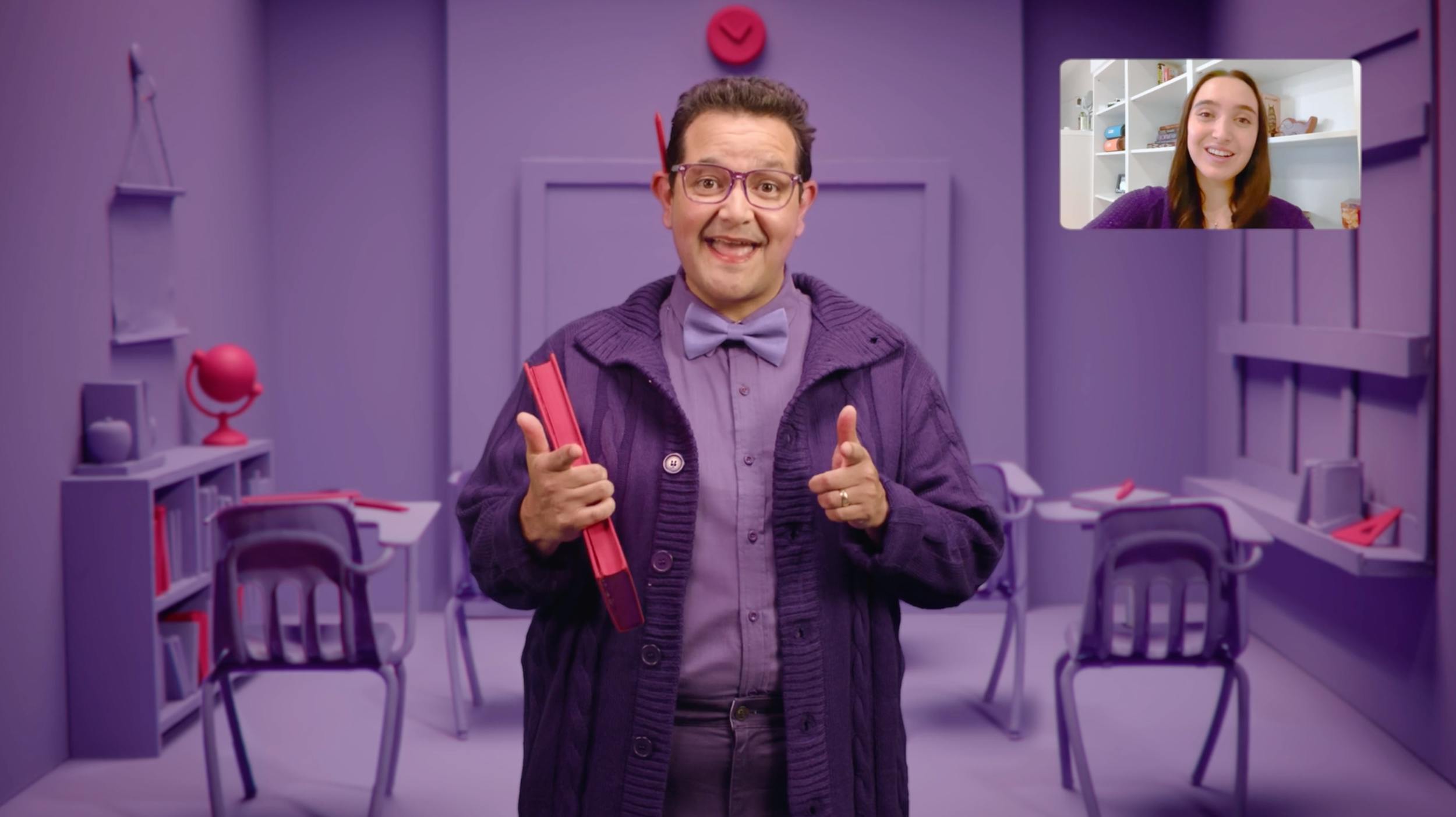 Television production frame of an educational video call, starring a goofy teacher in an all-purple classroom set design with picture-in-picture for remote instruction, used in video creation.