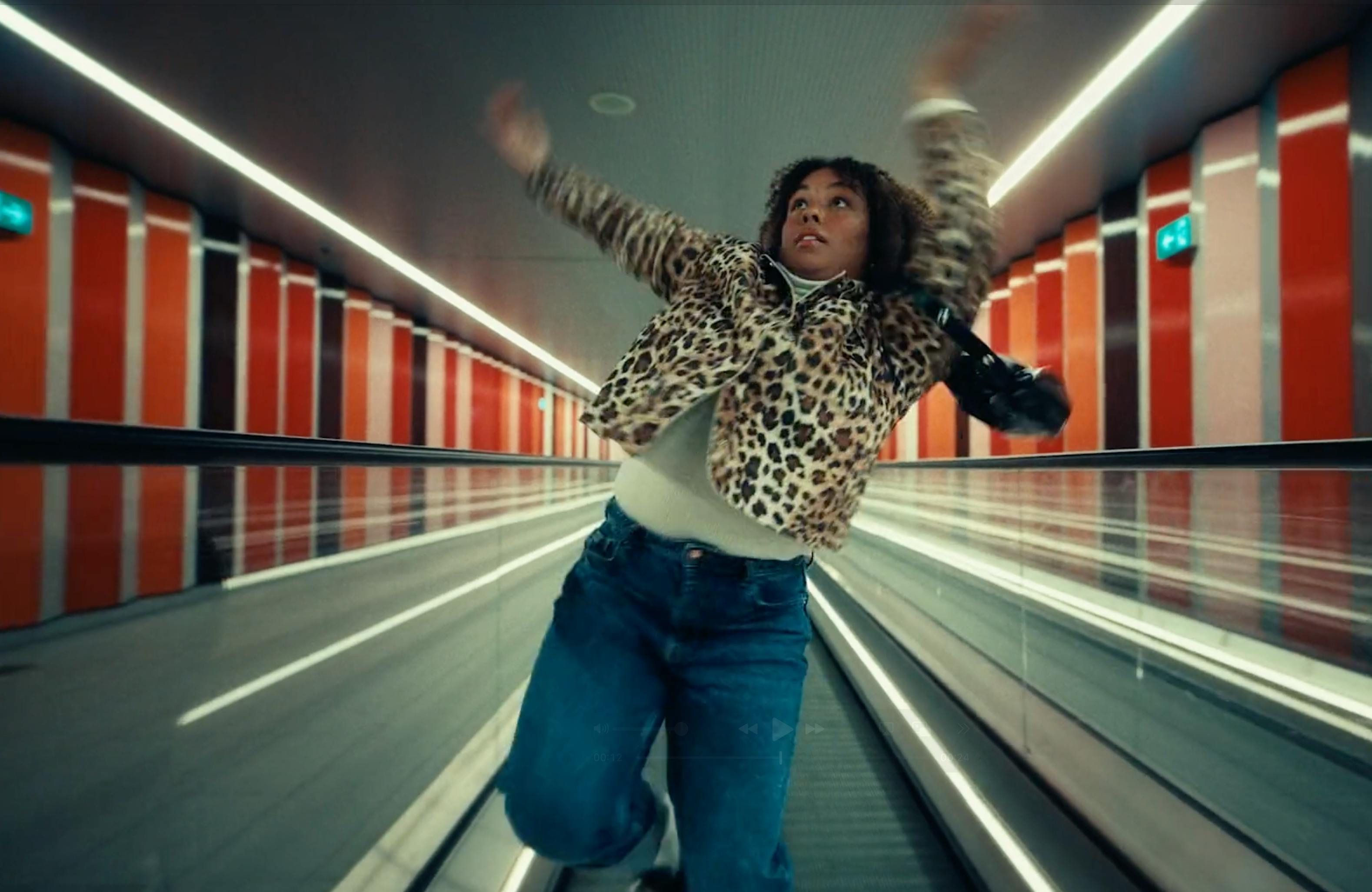 A person in a colorful shirt dancing or posing in an urban tunnel.