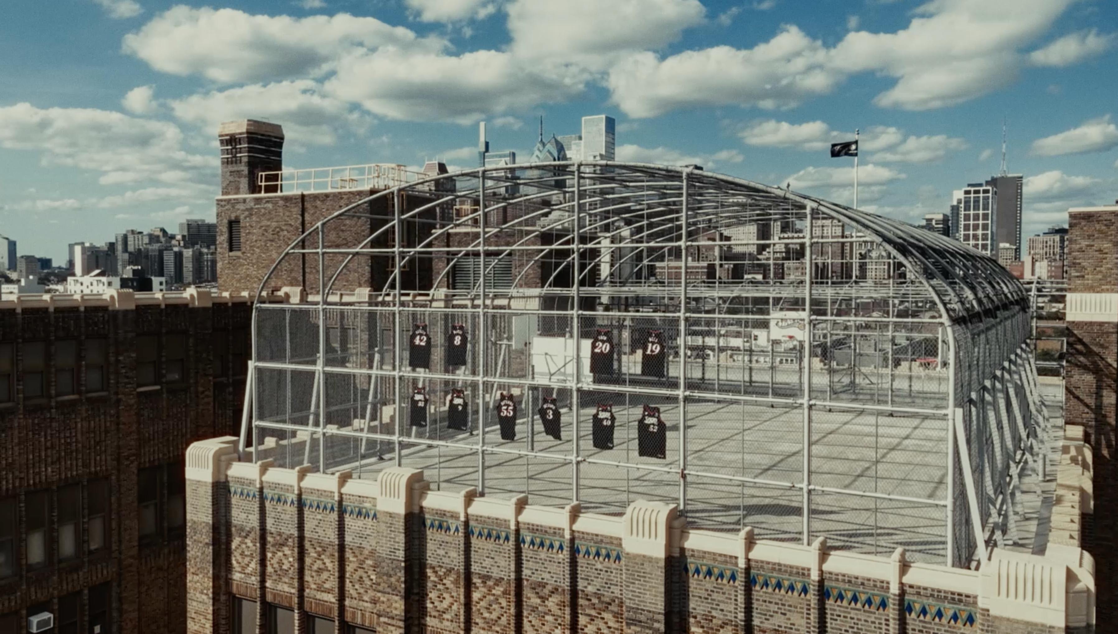 The thumbnail displays a wide architectural shot of a large, modern building or stadium under a blue sky.