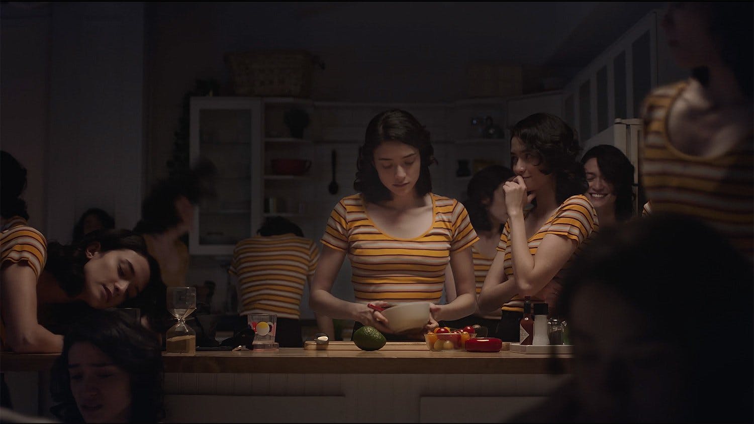 Video production composite of multiple identical actresses in a kitchen set, demonstrating special effects post-production and digital compositing for a commercial scene with intricate details.