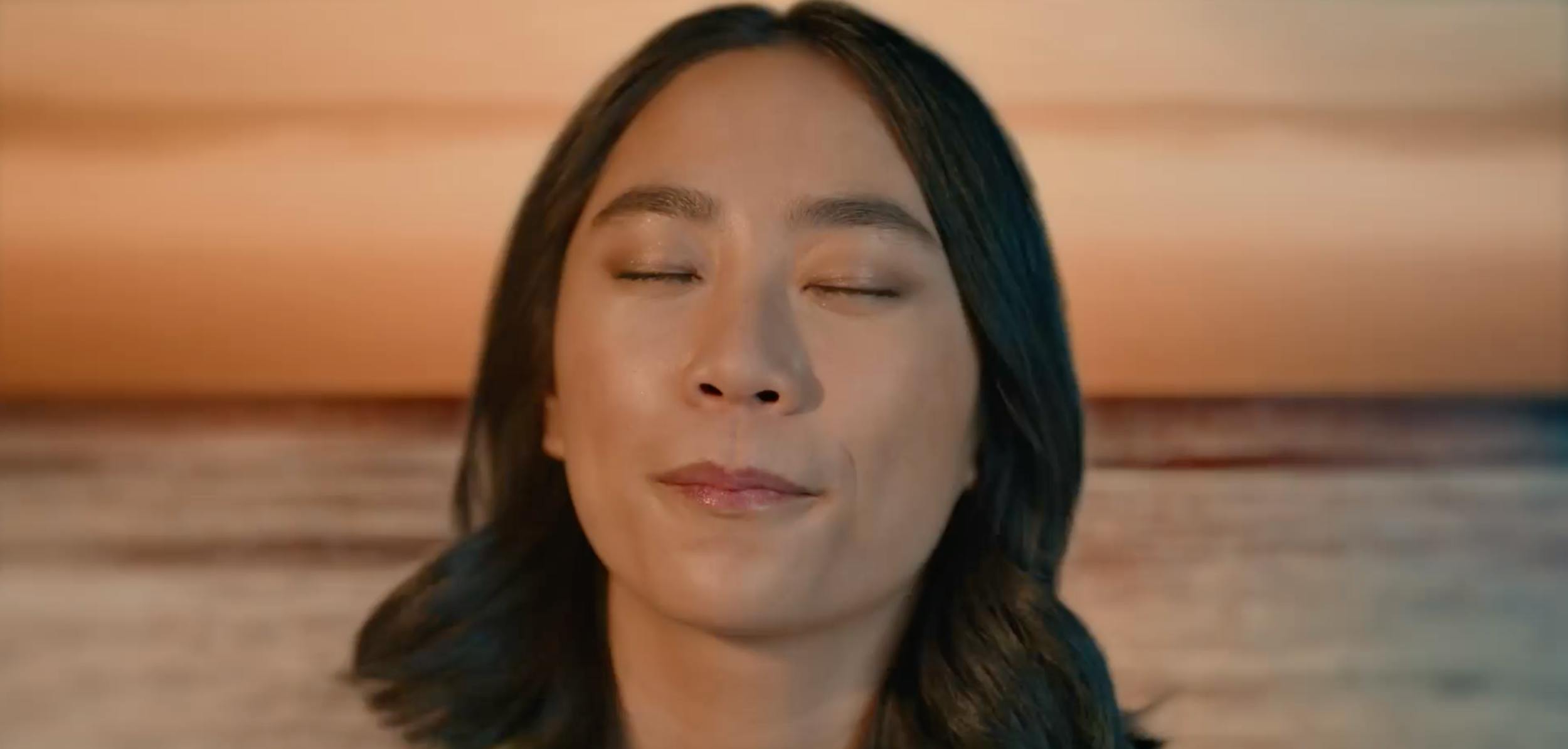Woman with calm expression at sunset by the ocean, capturing emotional storytelling and cinematic video production scenes