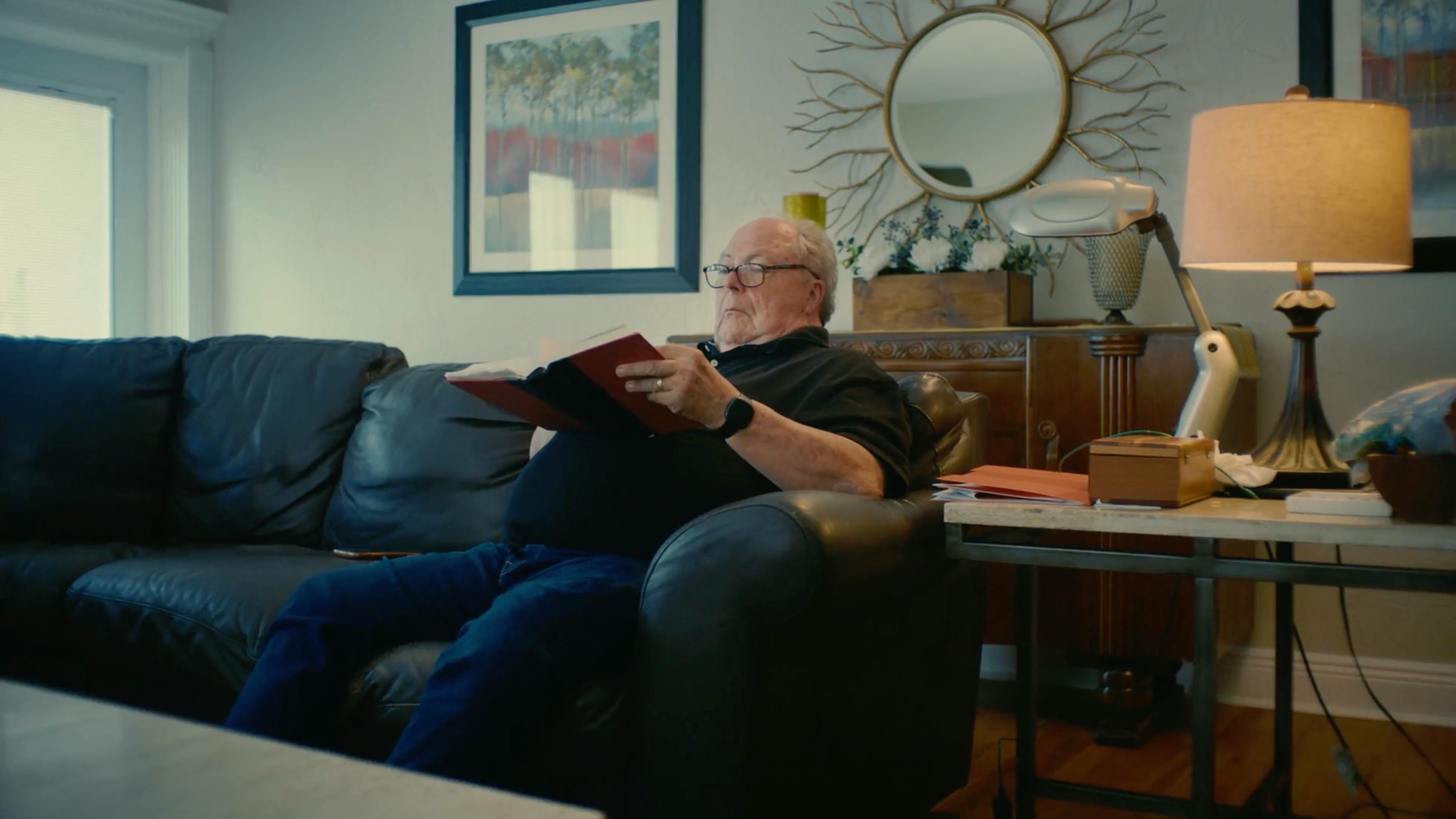Older man relaxing on a navy sofa in a modern living room, captured by a video production agency for video marketing for businesses