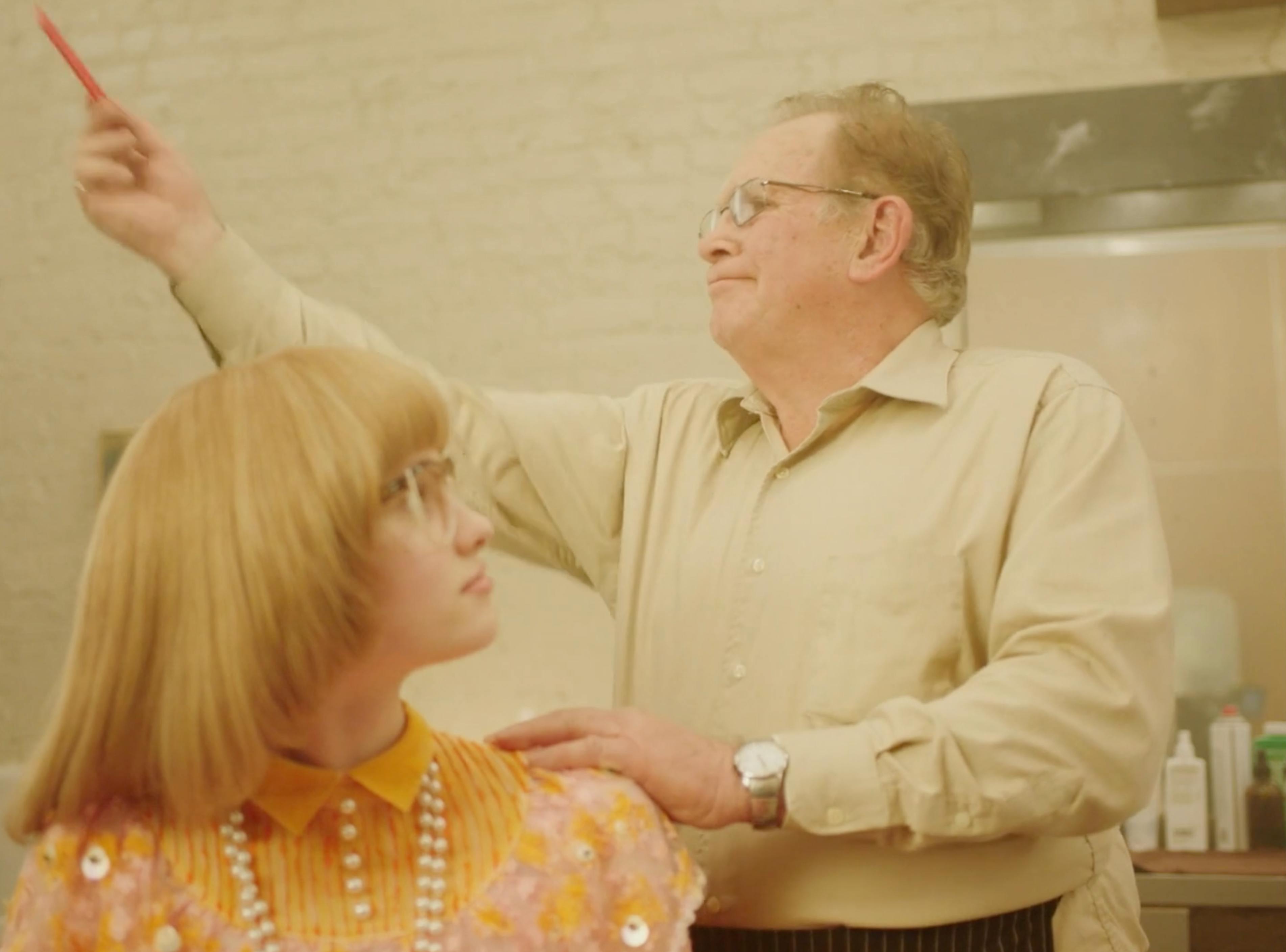 Blonde woman and older man in a salon scene from MICHAA fashion brand film production in New York