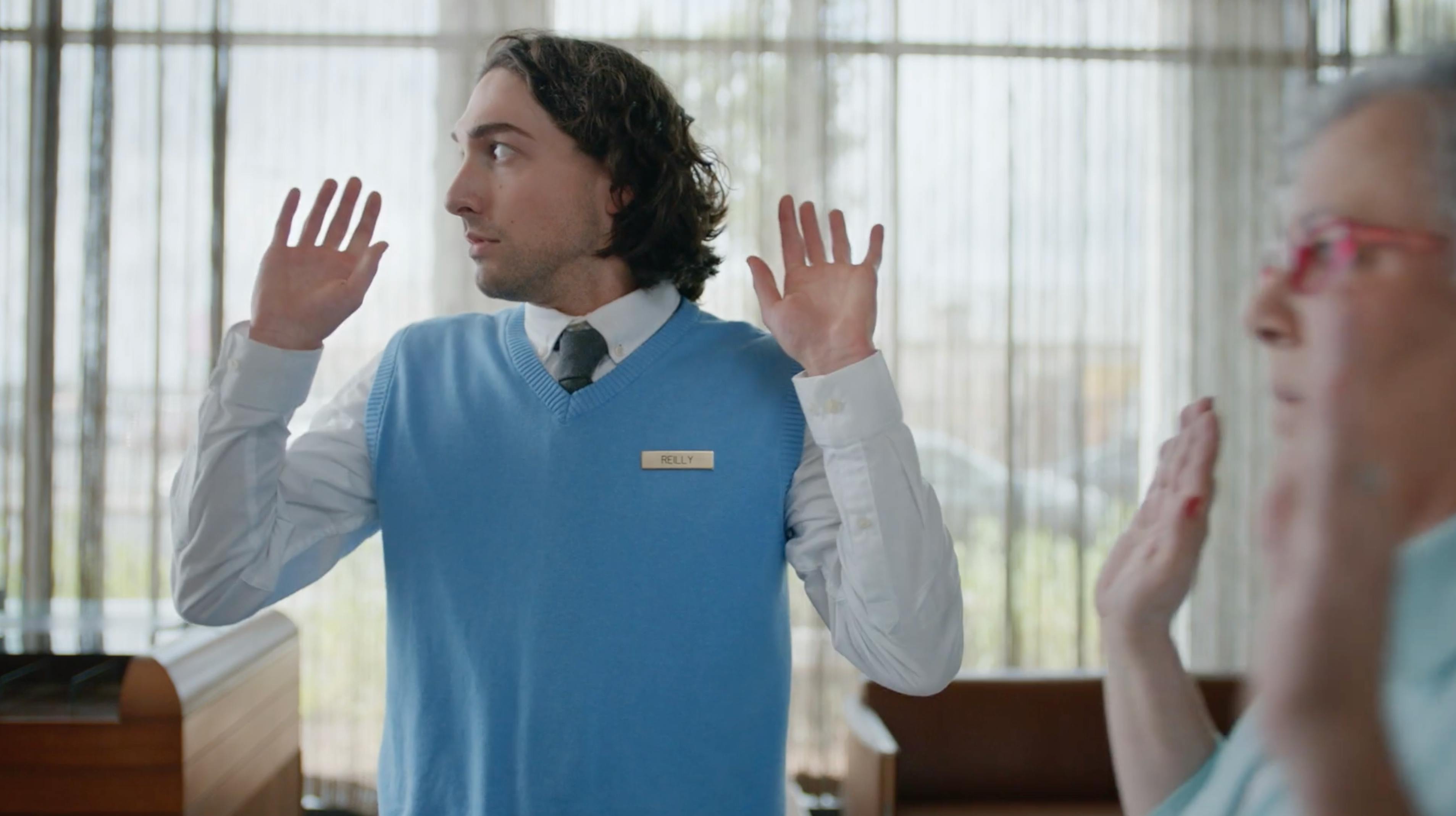 Man in a blue sweater raising his hands in a reception scene for a branded episodic content video producer NYC campaign