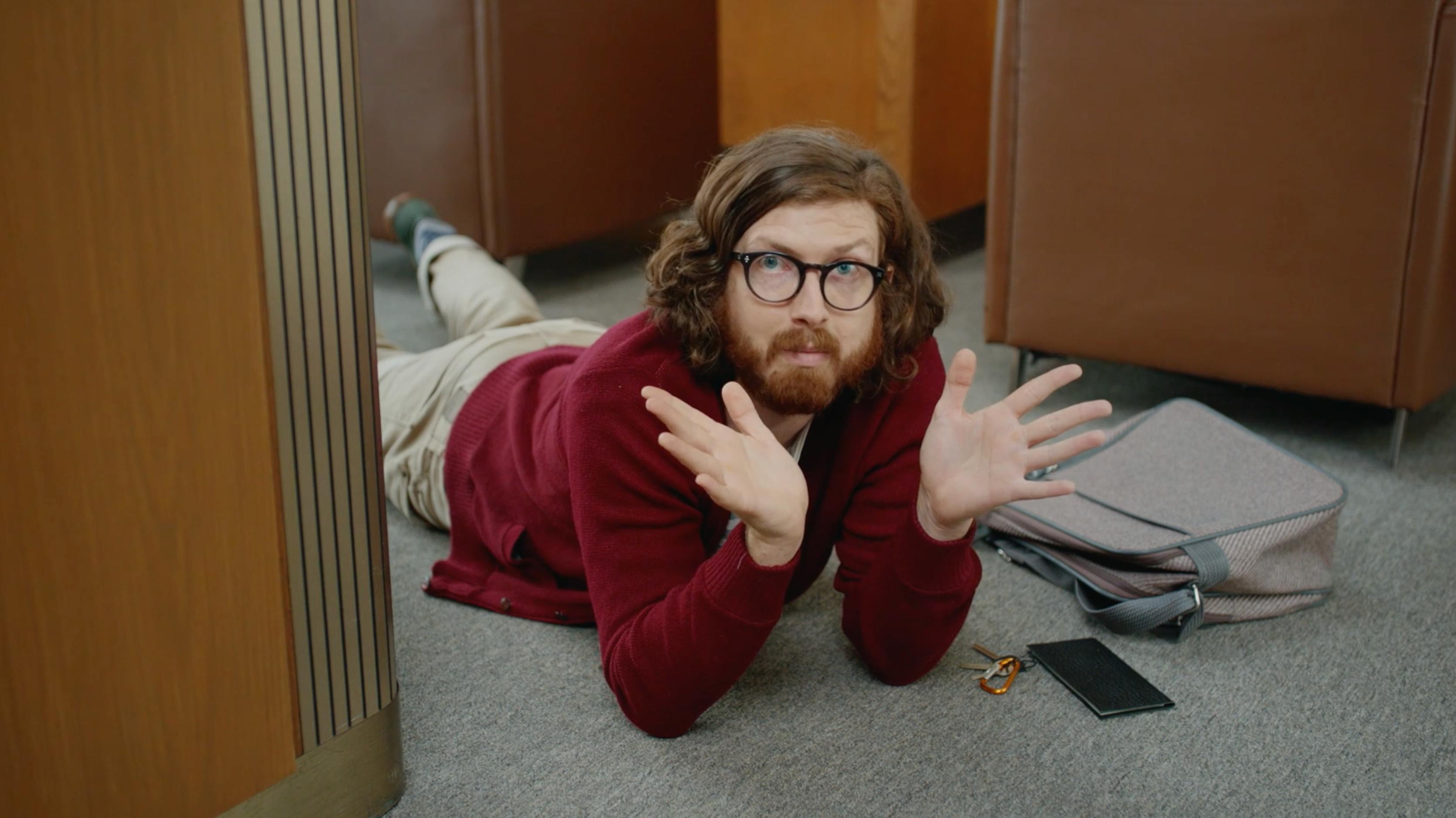 Man lying on an office floor in a comedic scene from a premium video production NYC campaign