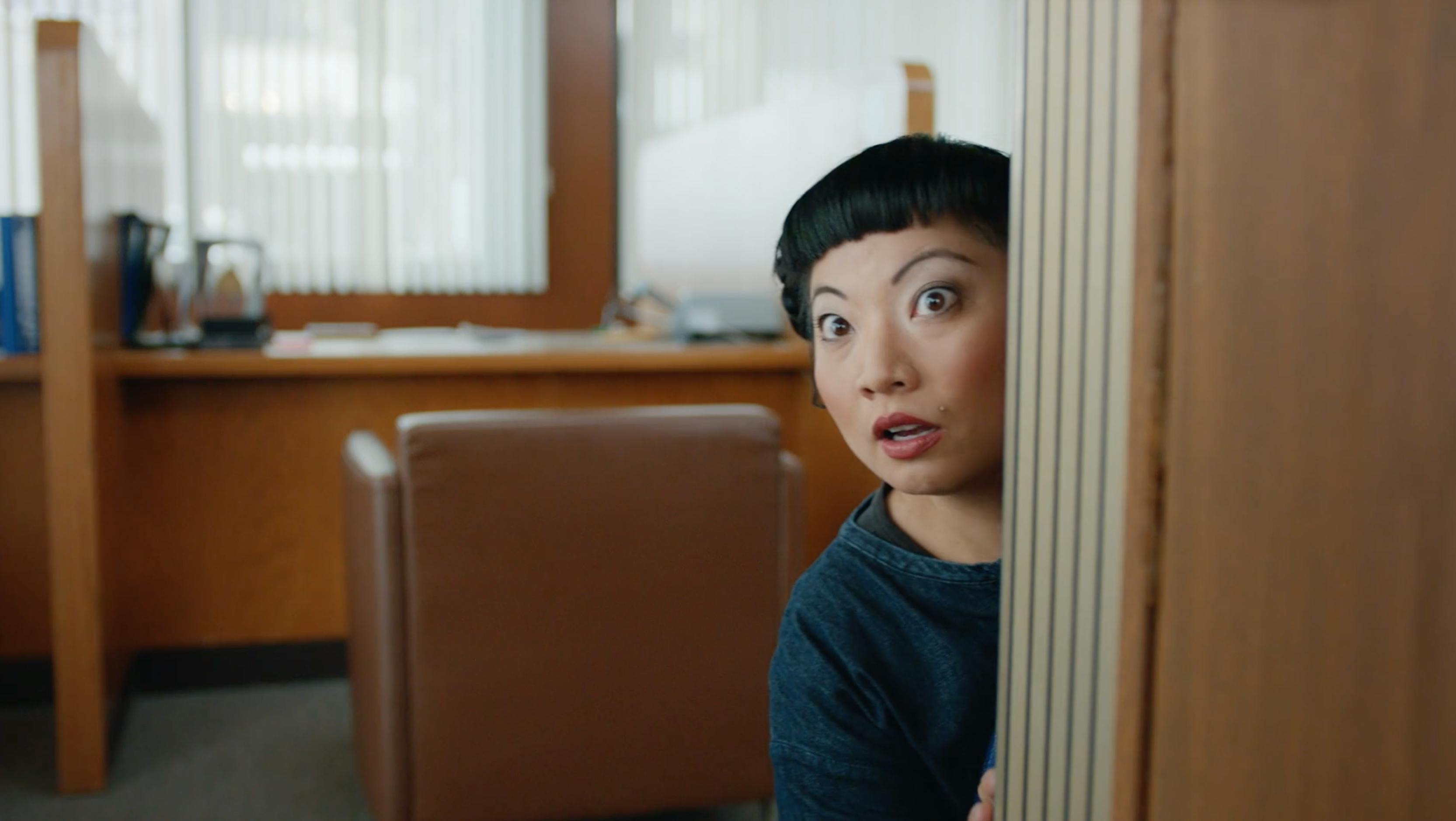 Woman peeking around a doorway in a cinematic office scene for high end video production services