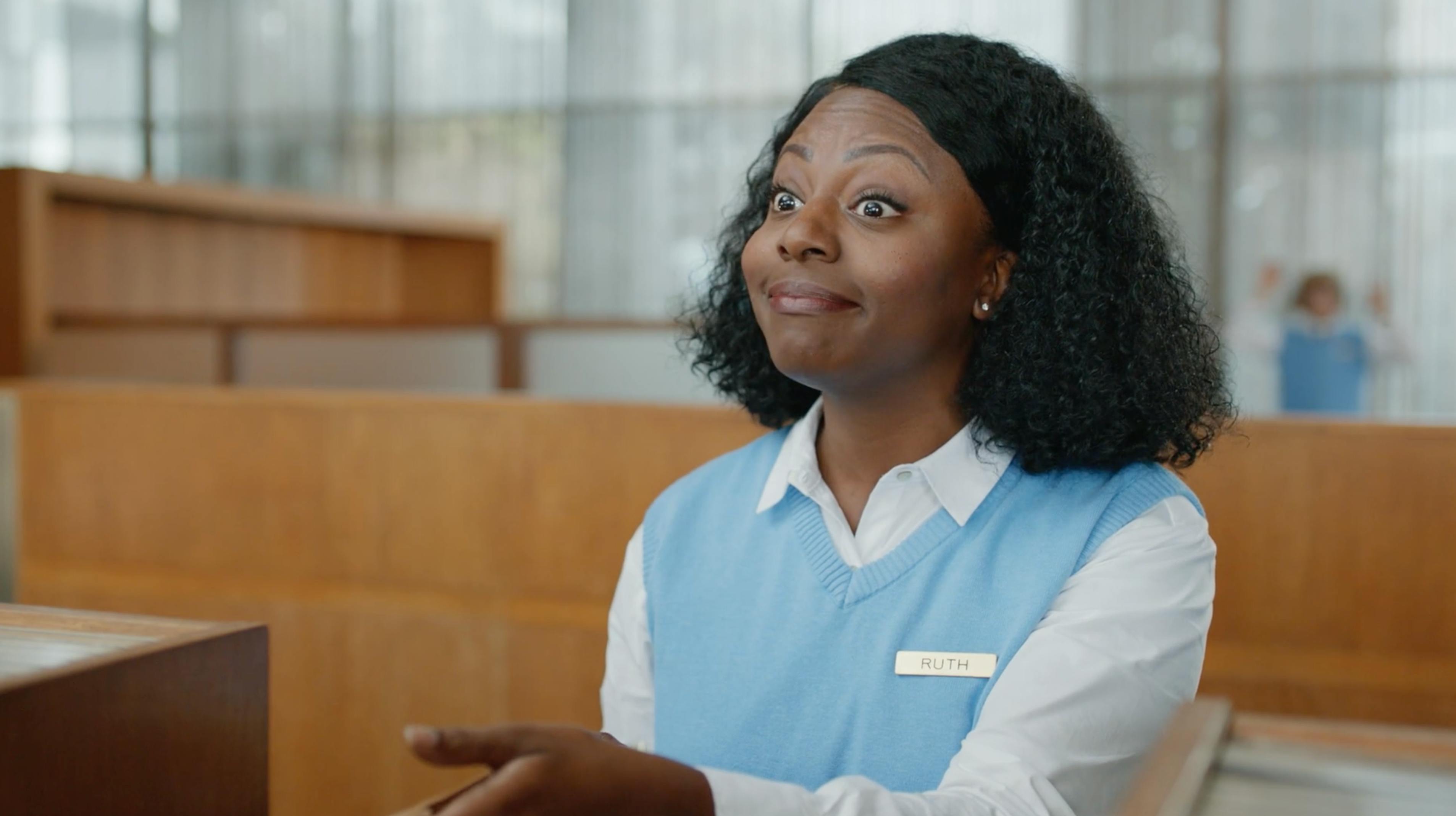 Woman in a blue uniform smiling at a reception desk in a branded episodic content video producer Montreal campaign